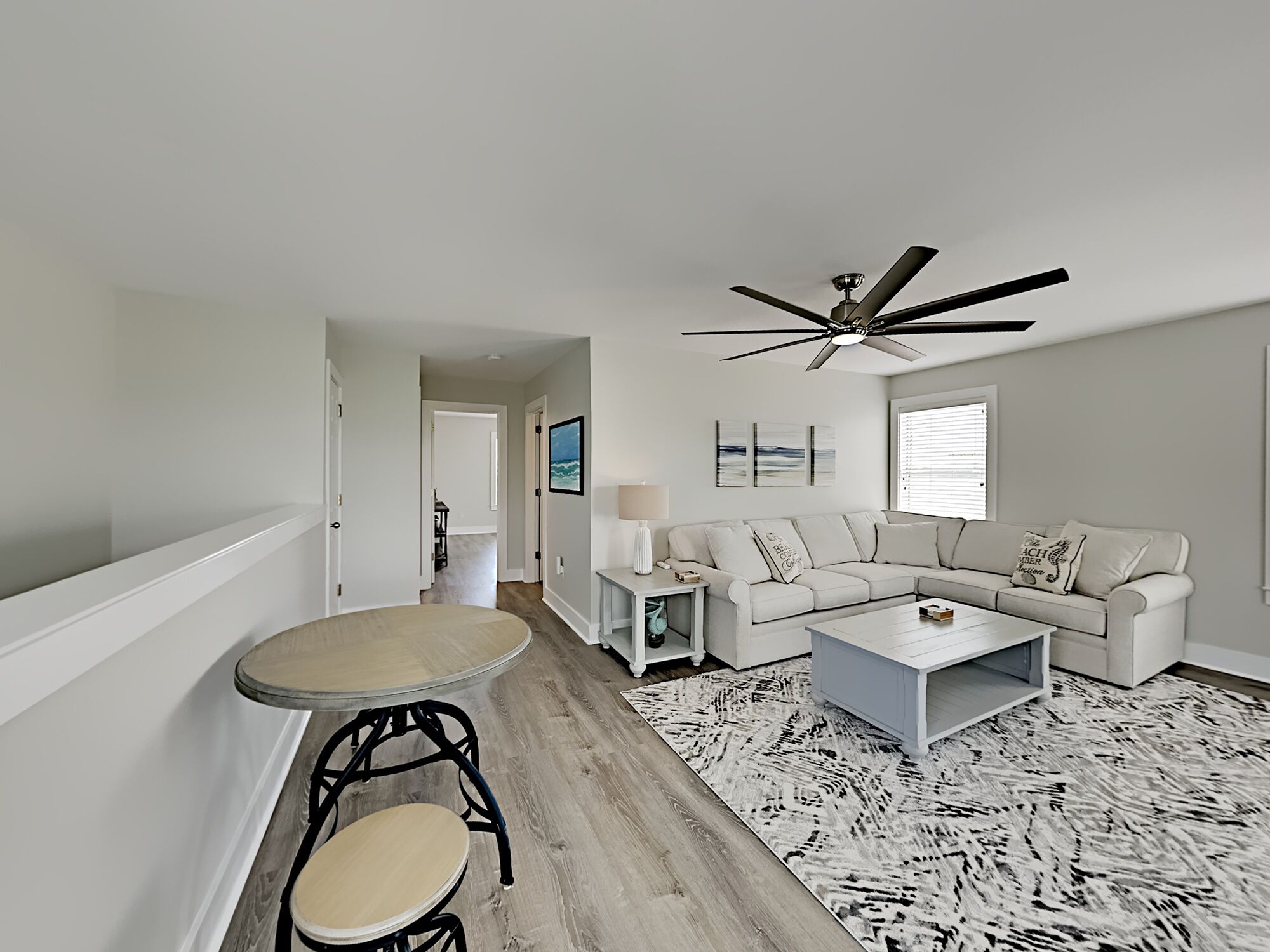 A modern living room with a white sofa, a coffee table, and a dining table with chairs.