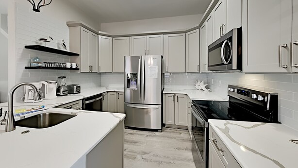 A modern kitchen with white cabinetry, stainless steel appliances, and a built-in microwave. - Sunny Days by Southern Vacation Rentals (Miramar Beach)