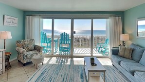 Ein Wohnzimmer mit Meerblick, ausgestattet mit einer Couch, Sesseln, einem Couchtisch und einem Teppich.