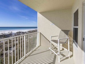A balcony with a view of the beach, a chair, and a window. - Cabana Club by Southern Vacation Rentals (Destin)
