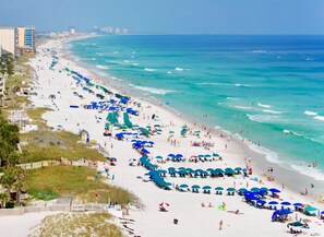 A beach with rows of umbrellas and beachgoers. - Cabana Club by Southern Vacation Rentals (Destin)