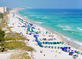 A beach with umbrellas and people.