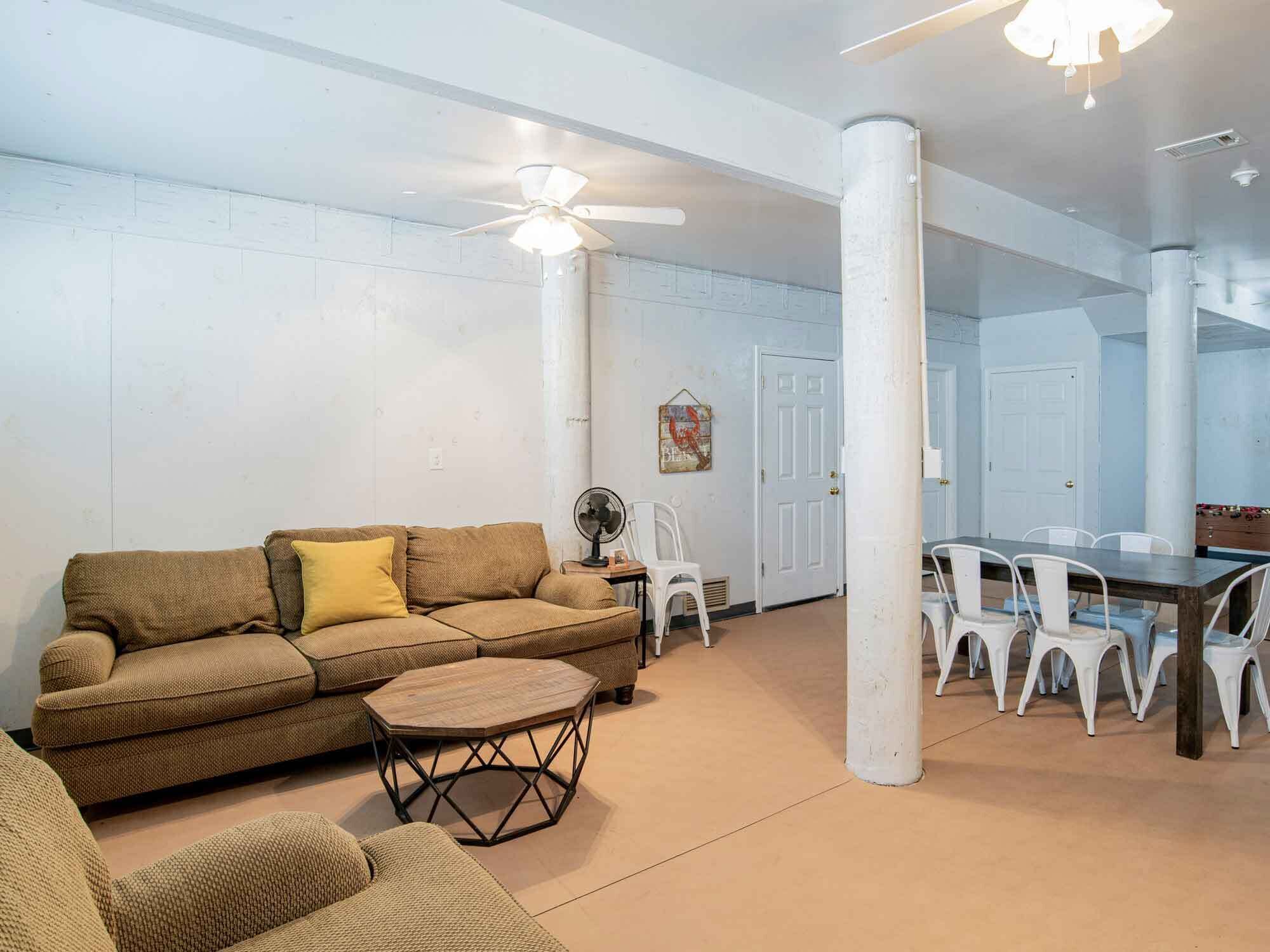 A spacious living area with a brown sofa, a round coffee table, and a dining table with white chairs.