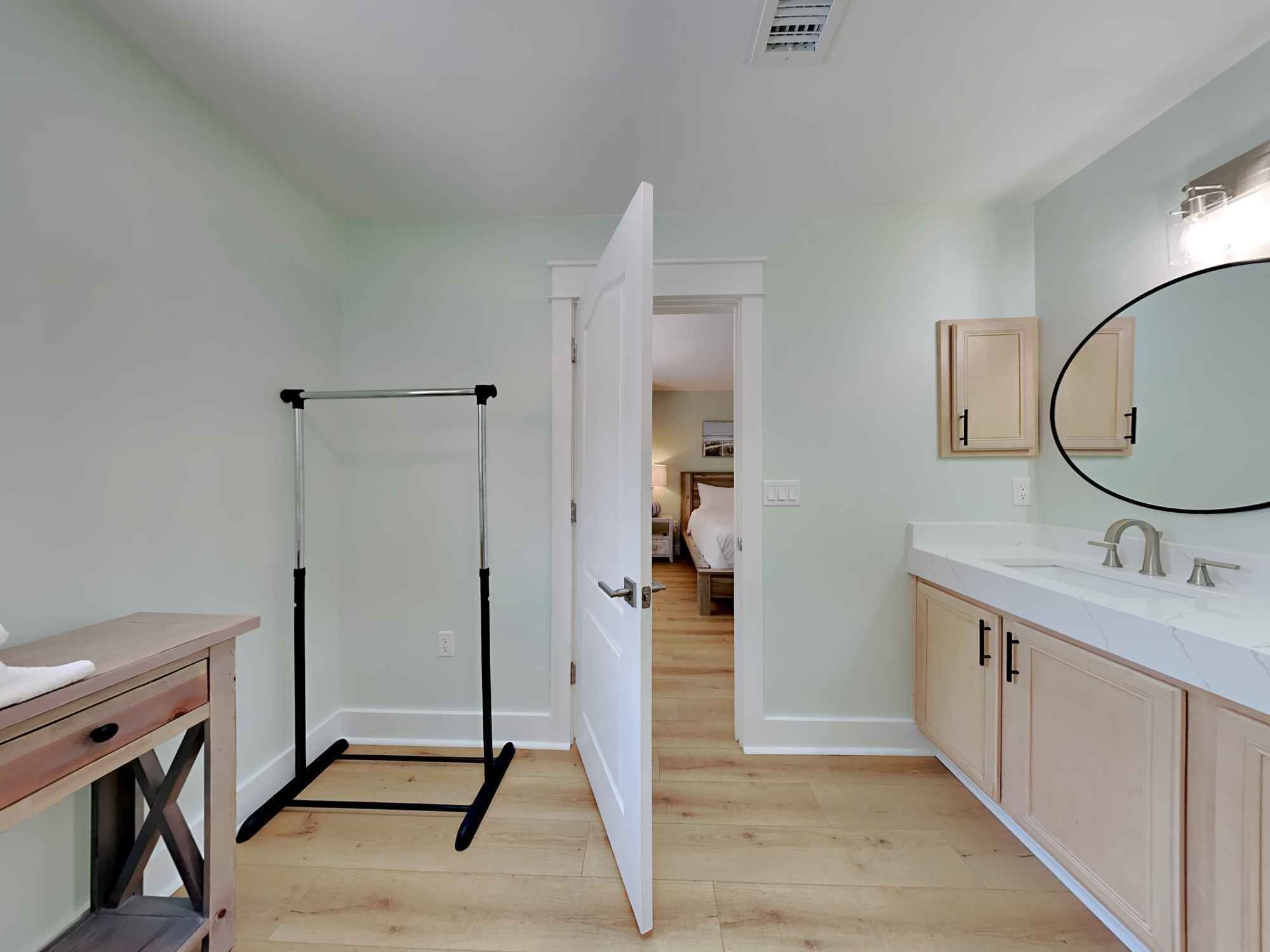 Un baño con tocador de madera, espejo y perchero para toallas.