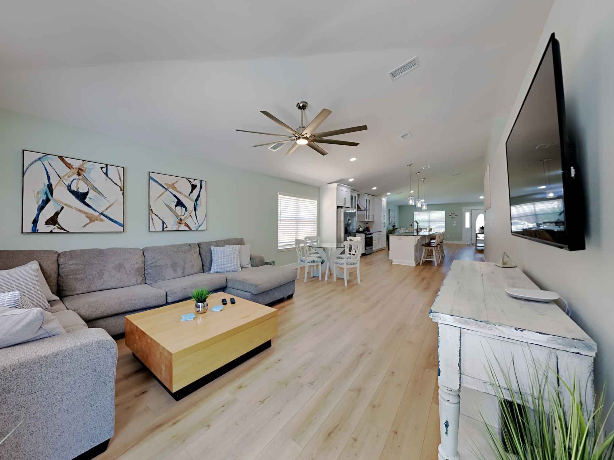 A modern living room with a grey sofa, wooden coffee table, and abstract art on the walls.