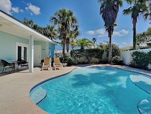 Relax by the pool surrounded by lush greenery and comfortable lounge chairs.