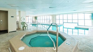 Una piscina interior con suelo de baldosas, una escalera de piscina y un banco.