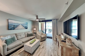 Uma sala de estar moderna com sofá, poltrona, mesa de centro e um quadro de um cais.