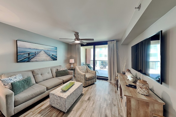 A modern living room with a sofa, armchair, coffee table, and a painting of a pier.
