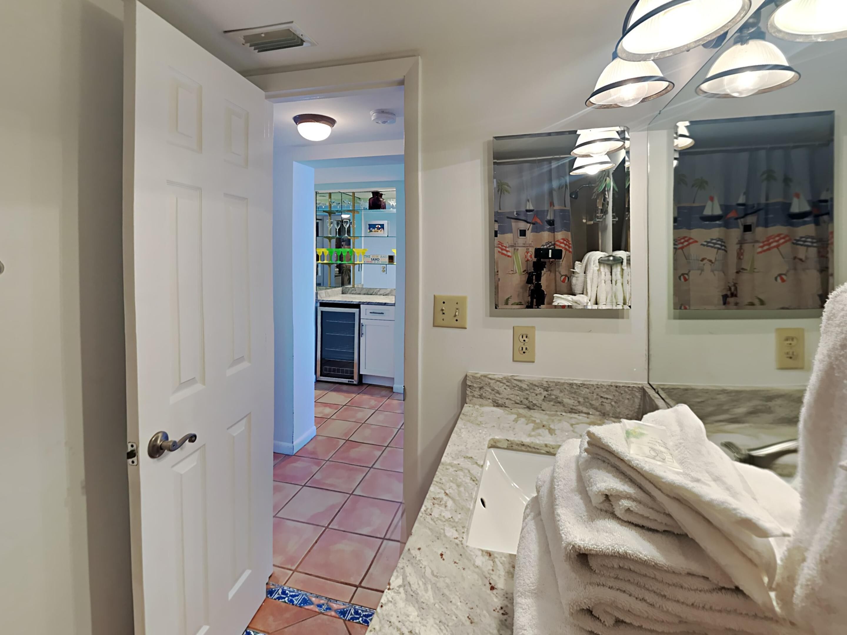 A bathroom with a sink, mirror, and towel stack.