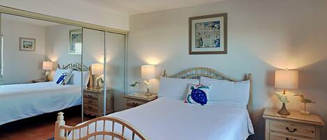A hotel room with a large bed, two bedside tables, a mirror, and a wall-mounted artwork.