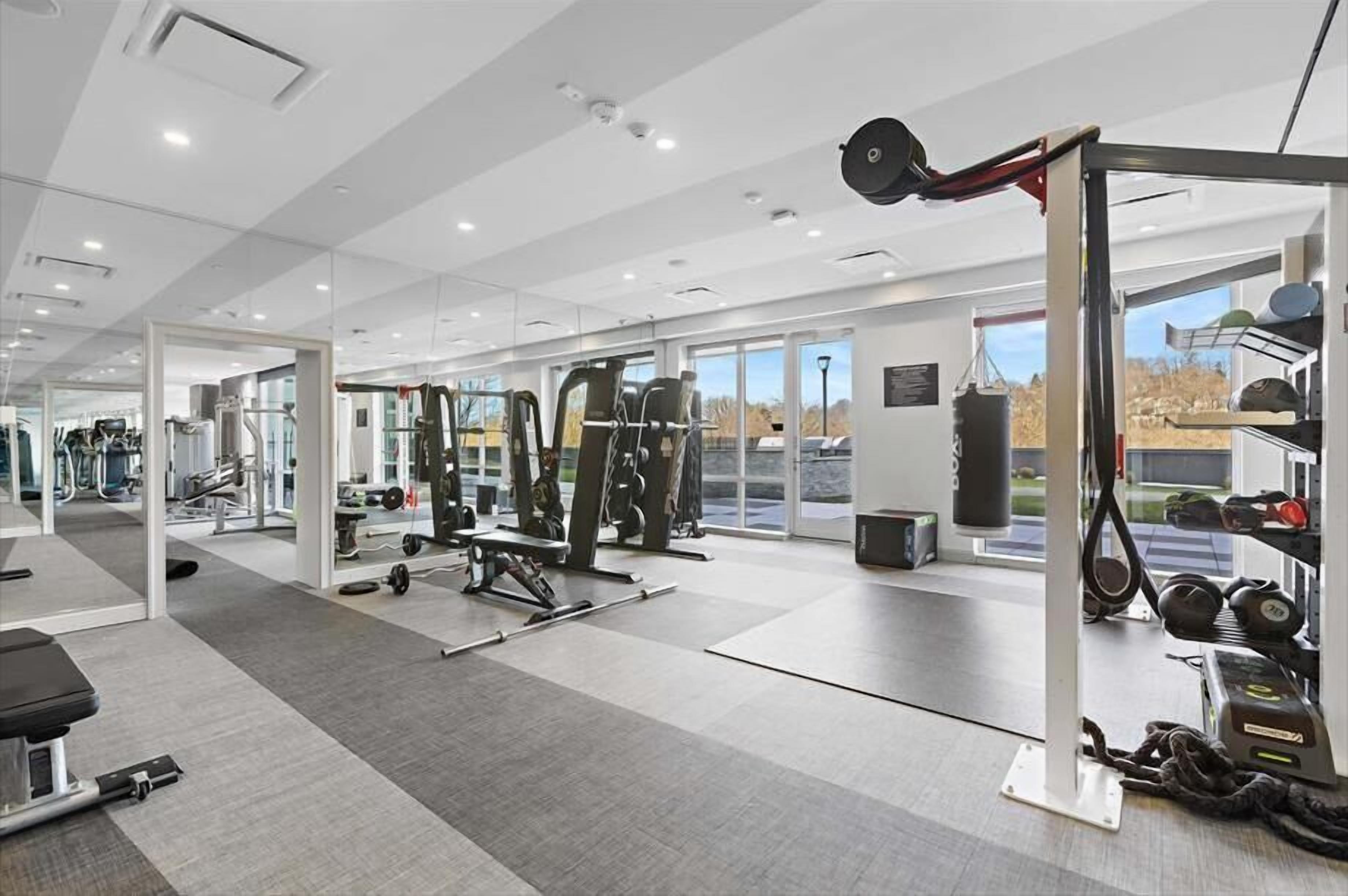 Ein modernes Fitnessstudio mit vielfältigen Trainingsgeräten, großen Fenstern und einem aufgeräumten, großzügigen Raum.