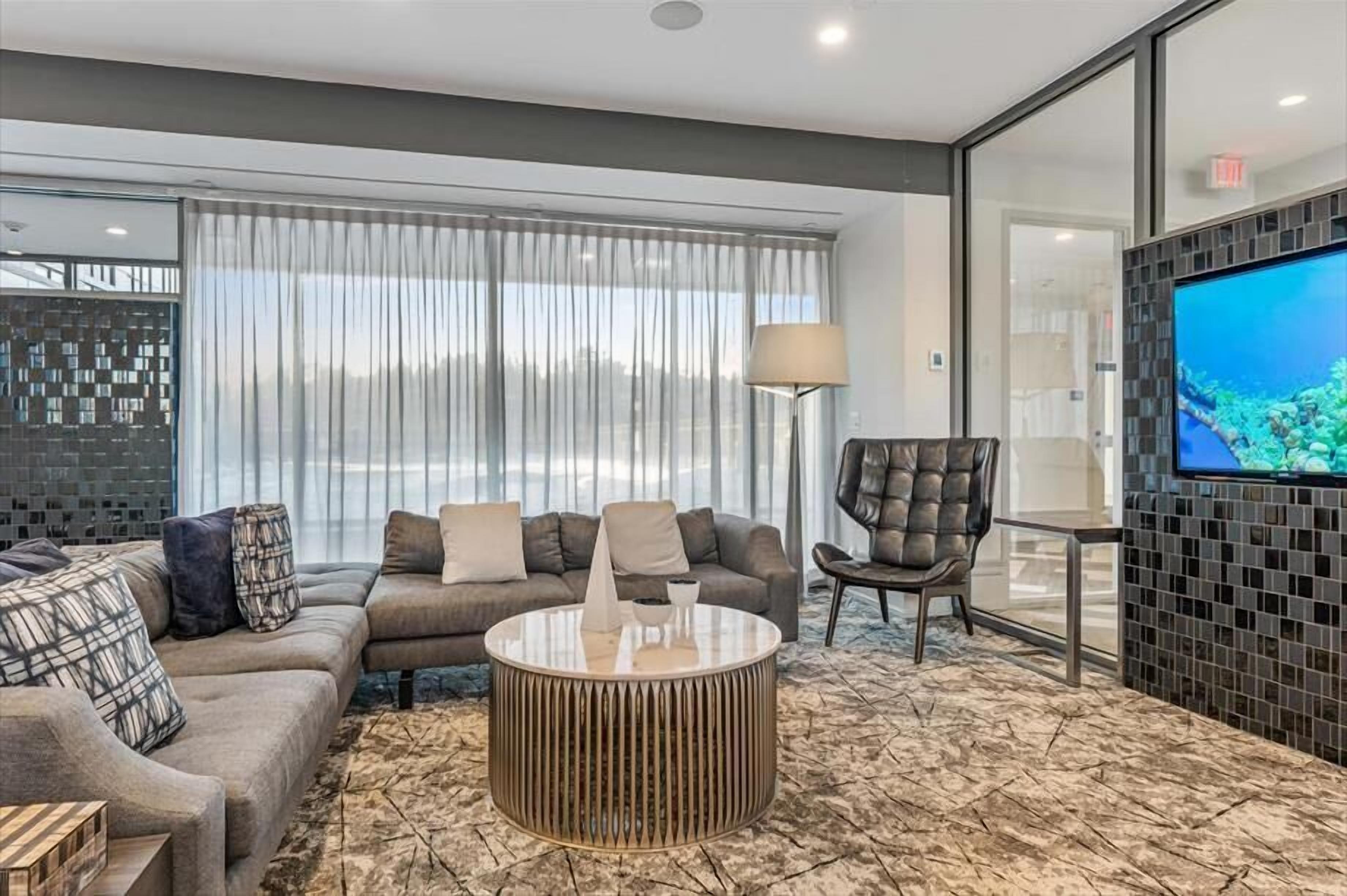 A modern living room with a sectional sofa, a round coffee table, and a TV mounted on the wall.