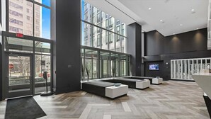 A modern lobby with large windows, a reception desk, and seating areas. - Private 1BR Apt | Parking | Gym & Pool | White Plains (White Plains)
