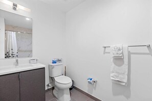 Ein modernes Badezimmer mit Waschbecken, Toilette und Duschbereich in Weiß.