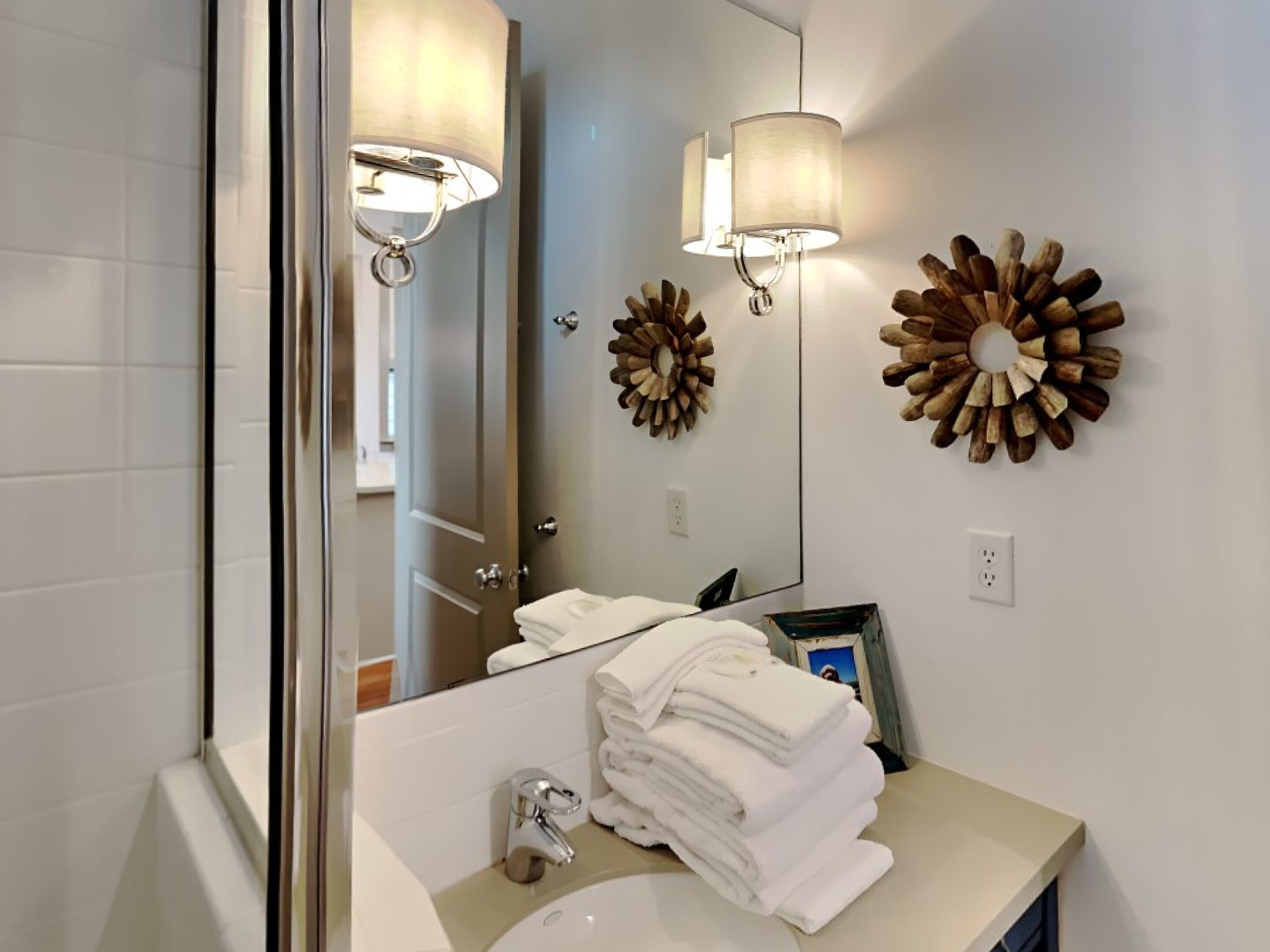 A bathroom with a sink, mirror, and two wall-mounted lamps.