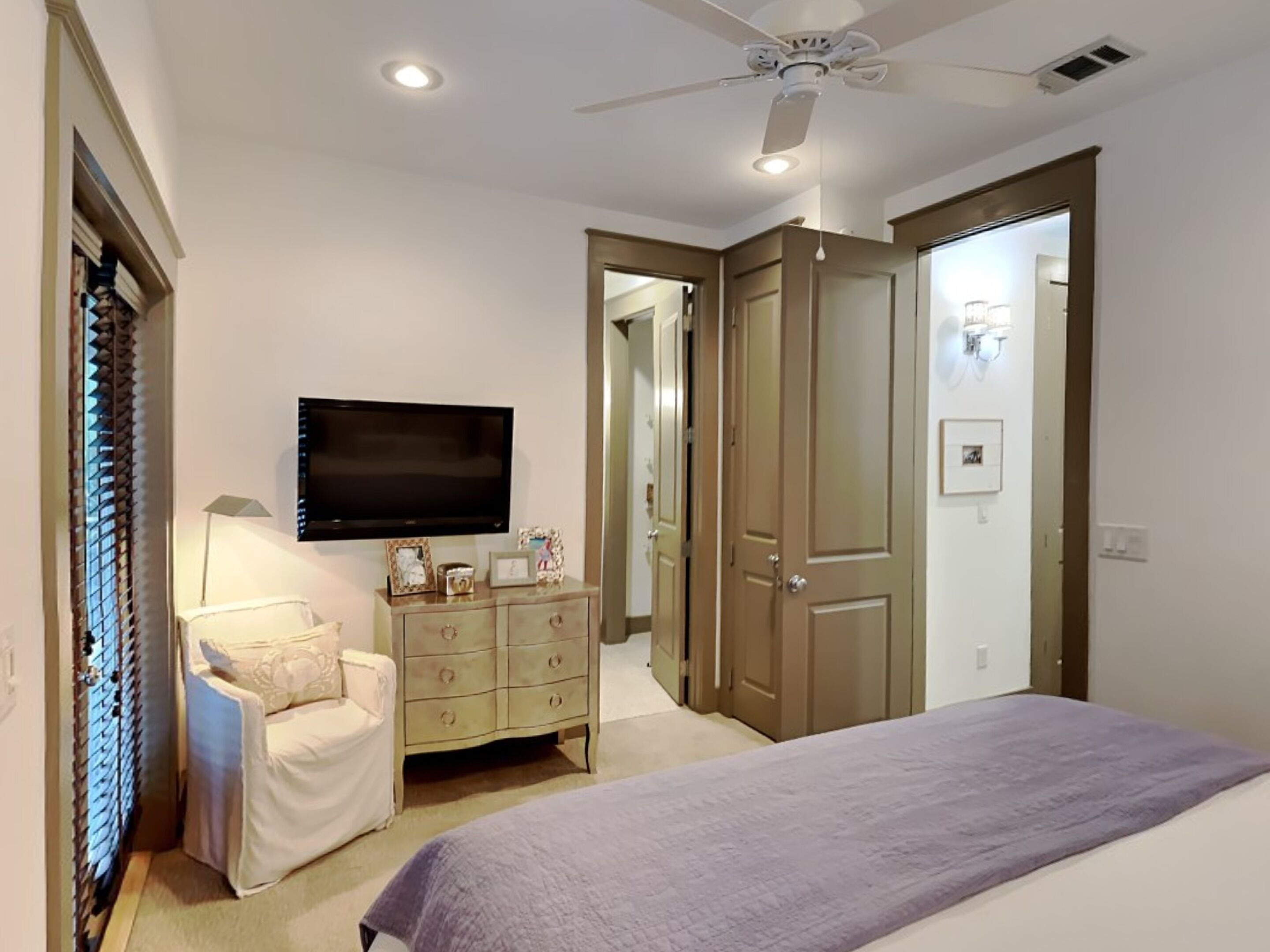 A bedroom with a bed, a dresser, a TV, and a ceiling fan.
