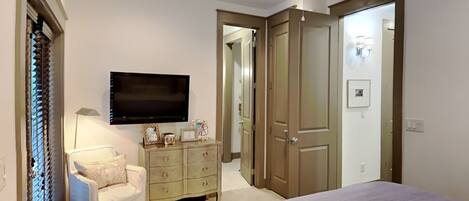 A bedroom with a bed, a dresser, a TV, and a ceiling fan.