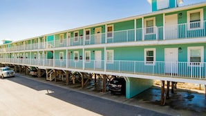 Un motel a più piani con diverse balconate e un'area di parcheggio con veicoli.