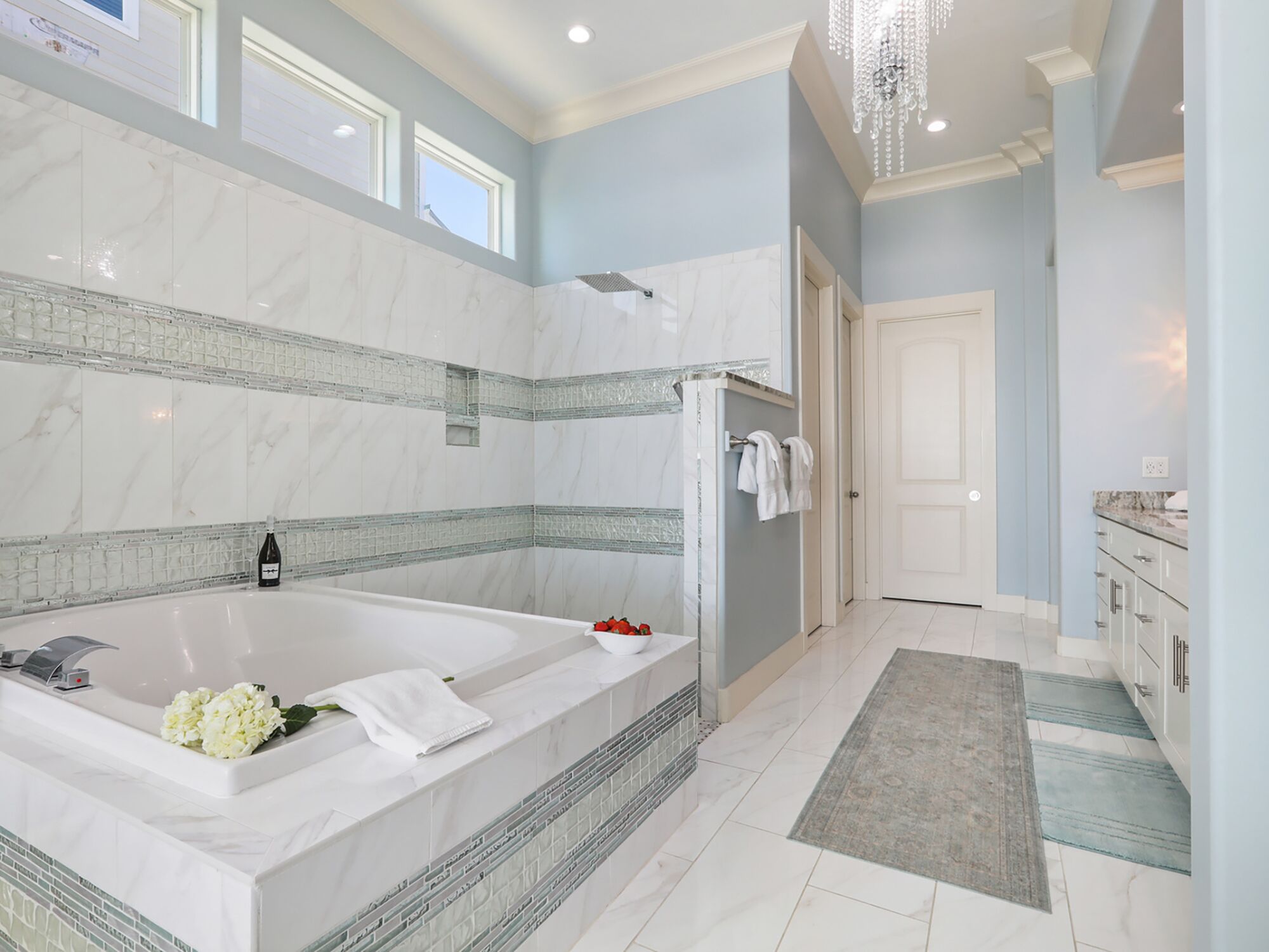 A spacious bathroom with a large bathtub, a shower, and a walk-in closet.