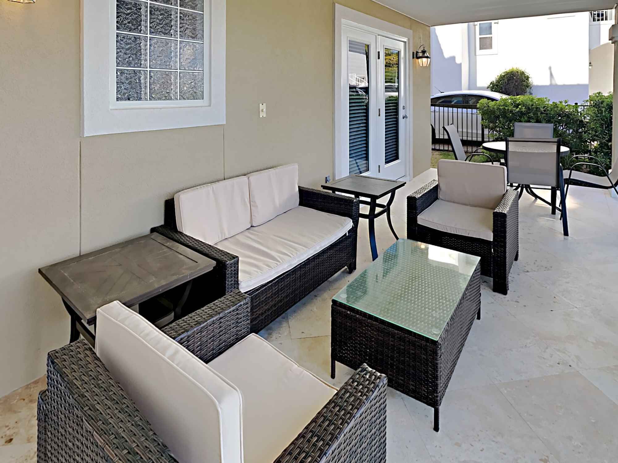 Ein überdachter Patio-Bereich mit Korbmöbeln, darunter eine Couch, Stühle und Tische.