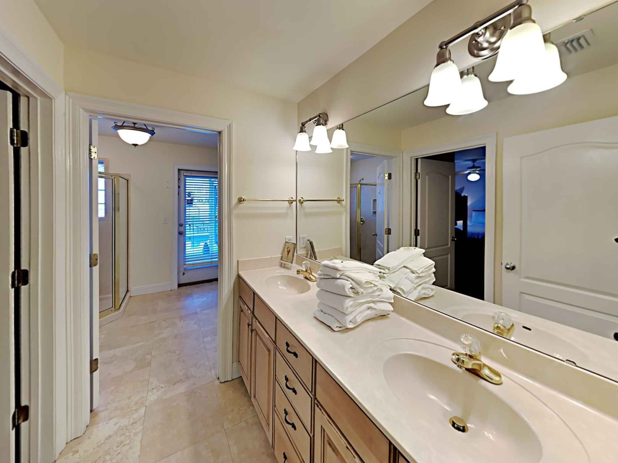 A bathroom with a large mirror, two sinks, and a towel rack.