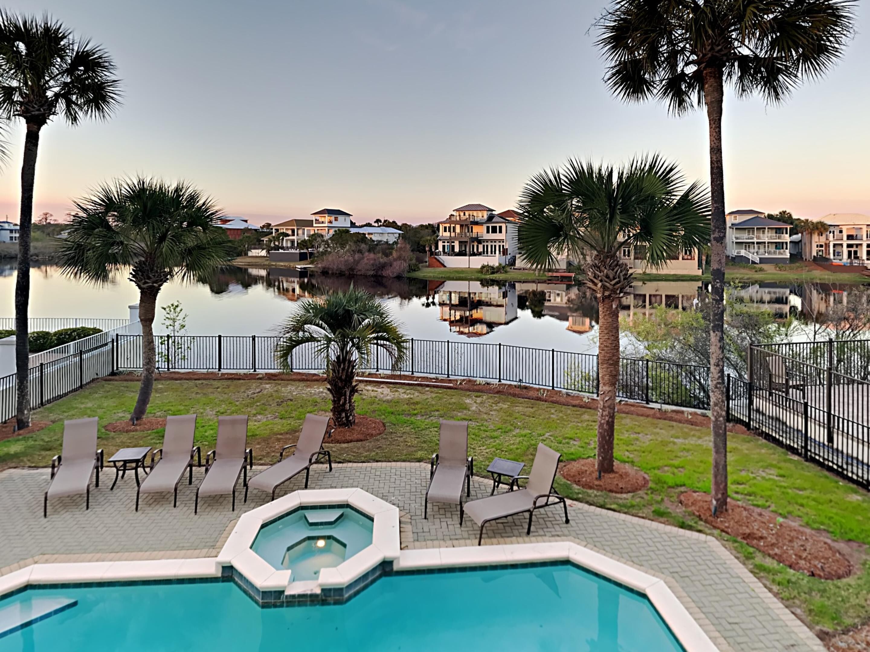 A swimming pool with lounge chairs and a view of a lake and residential buildings.