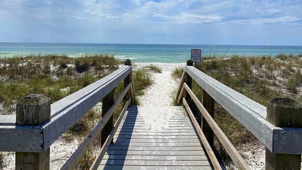 A wooden boardwalk leading to a beach with a sign indicating a notice area. - Margarita by Southern Vacation Rentals (Destin)