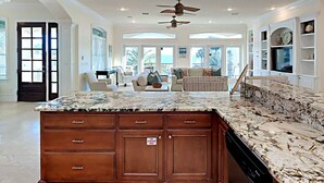 A spacious kitchen with a granite countertop, wooden cabinets, and a ceiling fan. - Margarita by Southern Vacation Rentals (Destin)