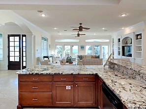 A spacious kitchen with a large island, wooden cabinets, and a ceiling fan.