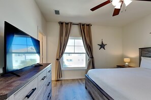 Relax in a stylish room with a large flat-screen TV, comfortable bed, and ceiling fan for a restful stay.