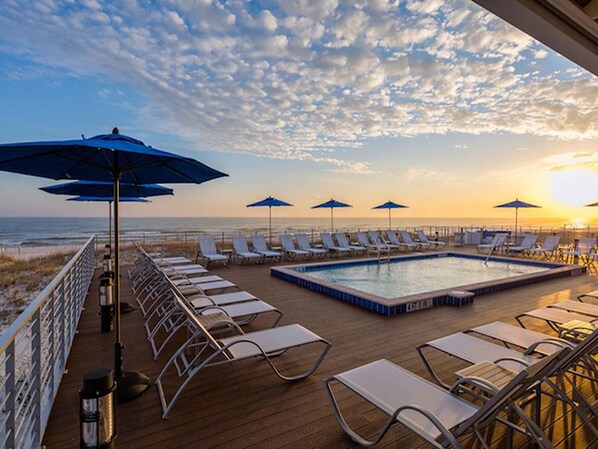 Relax by the oceanfront pool surrounded by lounge chairs and umbrellas.