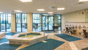 A spa area with a hot tub, large windows, and outdoor seating. - Phoenix on the Bay by Southern Vacation Rentals (Orange Beach)