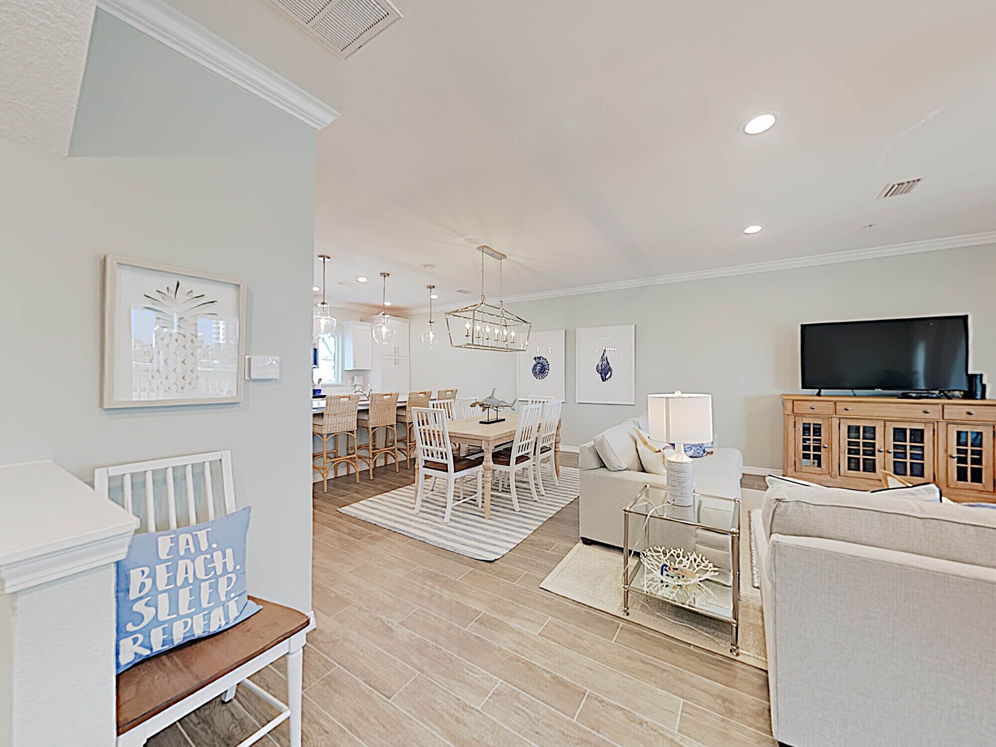 A spacious living room with a dining area, a television, and a kitchen in the background.