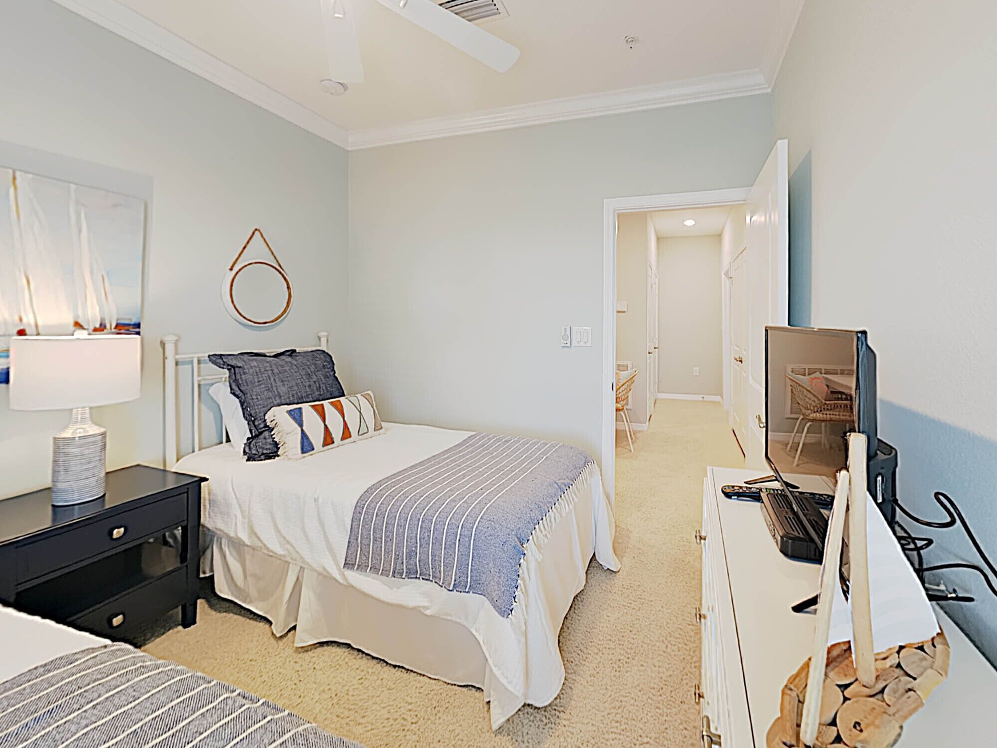 A bedroom with a bed, bedside table, lamp, and a television on a dresser.