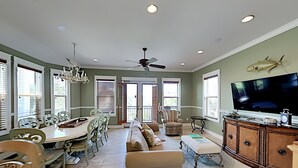 A spacious living room with a dining area, a large TV, and a ceiling fan. - Seabreeze Cabana by Southern Vacation Rentals (Panama City Beach)