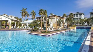 A swimming pool with lounge chairs and palm trees, surrounded by resort buildings. - Seabreeze Cabana by Southern Vacation Rentals (Panama City Beach)