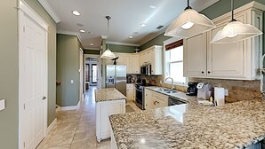 A kitchen with granite countertops, white cabinets, and pendant lighting. - Seabreeze Cabana by Southern Vacation Rentals (Panama City Beach)