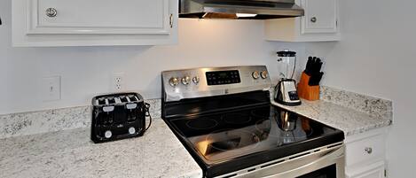 A kitchen with a stainless steel stove, a toaster, and a blender on the countertop.
