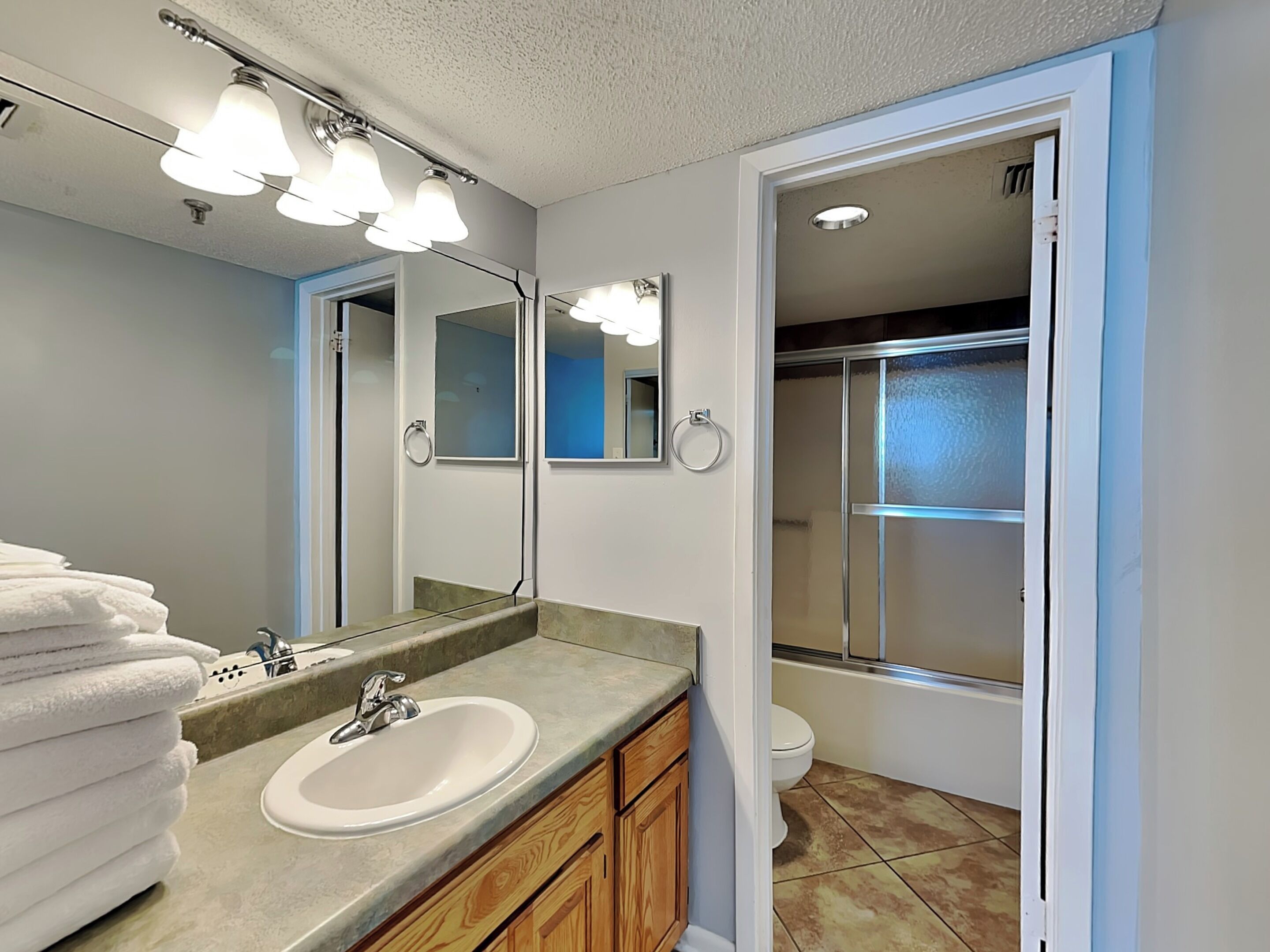 A modern bathroom with a sink, mirror, and towel stack.