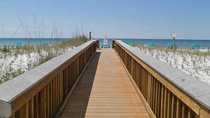 A wooden boardwalk leading to beach umbrellas and a sign. - Island Echos #3K by Southern Vacation Rentals (Fort Walton Beach)