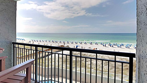 A balcony with a view of a beach with umbrellas and people. - Island Echos #3K by Southern Vacation Rentals (Fort Walton Beach)