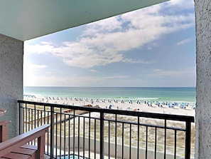 Ein Balkon mit Blick auf einen Strand mit Sonnenschirmen und Menschen.