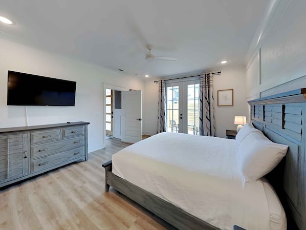 Relax in this serene bedroom with a large bed, dresser, and flat-screen TV.