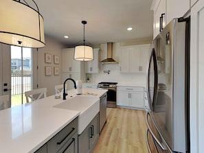 Enjoy cooking in this well-equipped kitchen with a central island, sleek faucet, and large overhead light fixture.