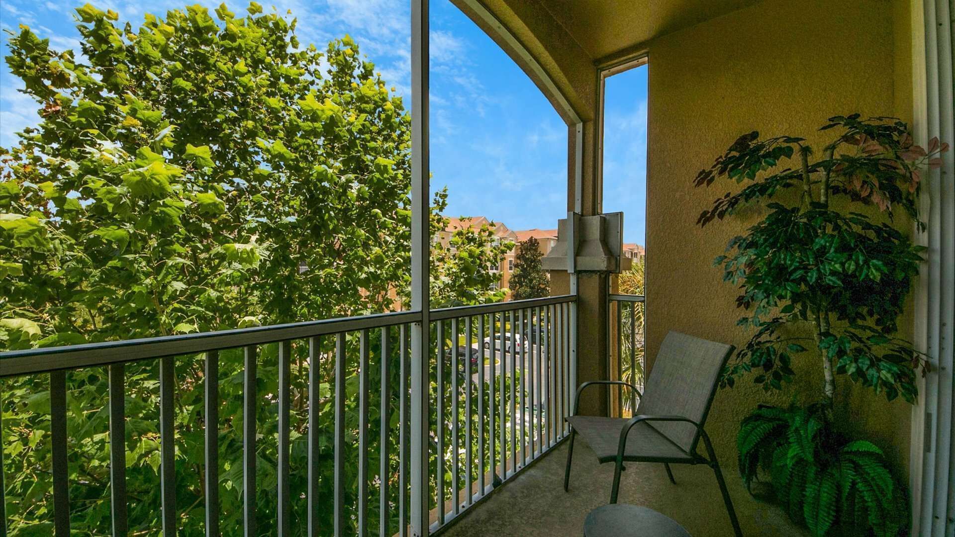 Een balkon met een metalen hekwerk, een stoel en een bloempot.