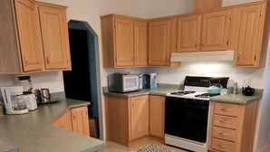 A compact kitchen with wooden cabinets, a microwave, a stove, and a coffee maker. - Up Country Ranch House down a quiet lane (Mule Creek)