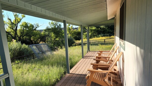 A covered porch with wooden benches and a view of a natural landscape. - Up Country Ranch House down a quiet lane (Mule Creek)