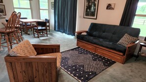A living room with a sofa, wooden armchair, and a dining table with chairs. - Up Country Ranch House down a quiet lane (Mule Creek)