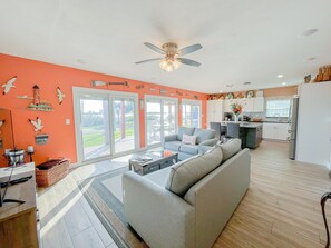 A spacious living room with a grey sofa, a coffee table, and a large window.